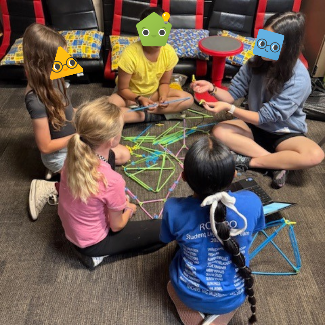 A group of students sitting on the floor and building with Strawbees.